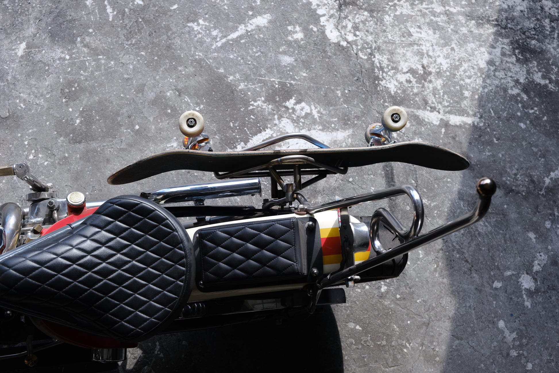 Edward Richie Motorcycle Skateboard rack in stainless steel with a skateboard in it mounted on a custom Harley top